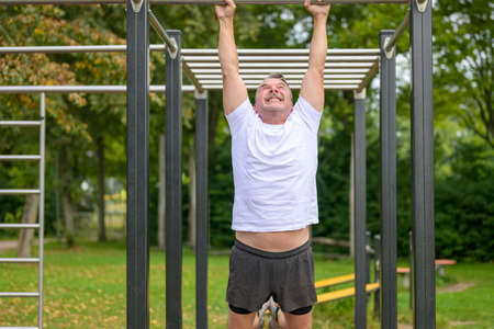 Senior man working out on parallel bars in a park in spring in a healthy lifestyle and fitness...
