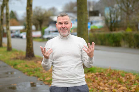 Upset or exasperated man gesturing with his fingers as he looks at the camera with a stressed...