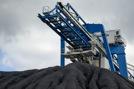 Huge mountain of black coal and a steel structure for transporting coal in a concept of energy...