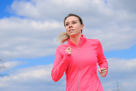 Blonde woman jogging in the countryside in springの写真素材