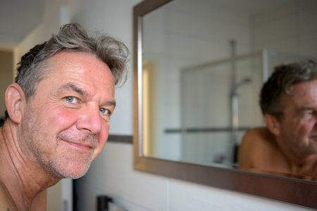 Nice attractive man early in the morning in the bathroom looks friendly at the cameraの写真素材