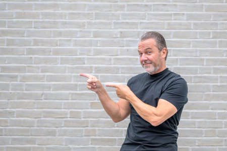 Portrait of an attractive friendly man pointing to the left side and looking to cameraの写真素材