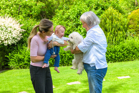 A joyful moment captured as three generations come together in a lush garden. A young mother holds...