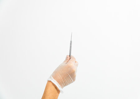 Close-up of a podiatrist's hand with gloves holding gouge on a white backgroundの写真素材