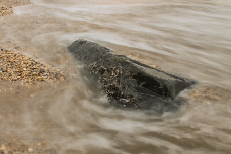 Wave over a rock at the beachの素材