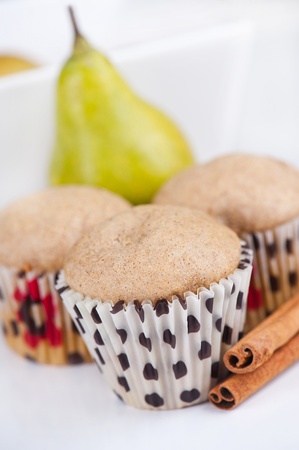 Three muffins on white plate with pear in the background, selective focusの写真素材