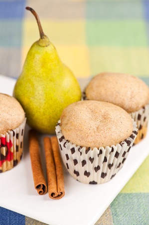Three muffins on white plate with cinnamon and pear in the background, selective focusの写真素材