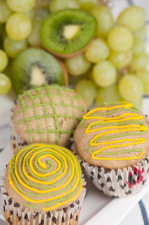 Three muffins on white plate with grapes and kiwi, selective focusの写真素材