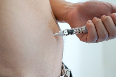 men diabetes patient using insulin injection pen in abdomen area on white background isolateの写真素材