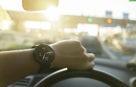 business man look smartwatch show calculation calories distance pedometer per day in car with traffic jam with sun lightの写真素材