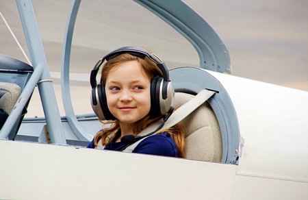 Girl sitting in two seater airplane smiling and ready to fly