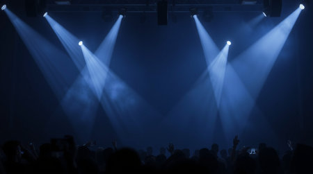 silhouette of concert crowd in front of a stage with blue lights
