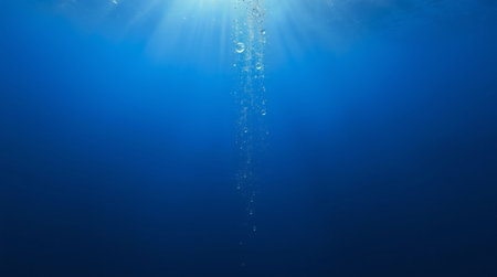 Underwater view of a deep blue sea with sunlight rays and bubbles