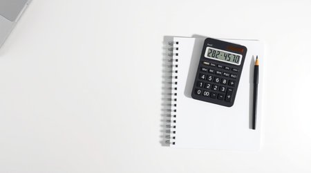 Calculator with pencil and notebook on white background. Top view