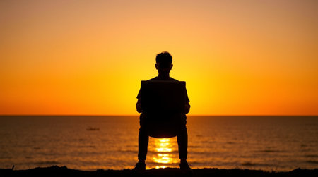 Silhouette of a man with a laptop against the backdrop of the sea