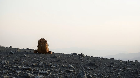 Backpack on the top of a mountain in the rays of the rising sun