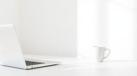 Laptop and coffee cup on white table in office with copy space