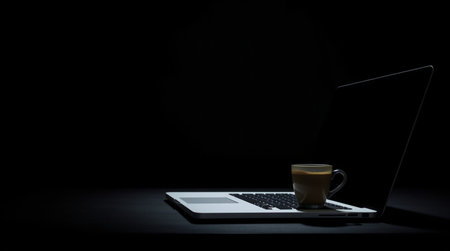 Laptop with a cup of coffee on a black background. Business concept