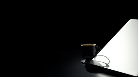 Coffee cup and tablet on black background with copy space.
