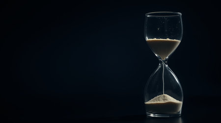 Hourglass with sand on a black background. Time passing concept.