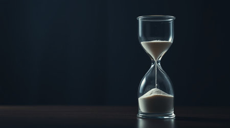 Hourglass with sand on a dark background. Time passing concept.