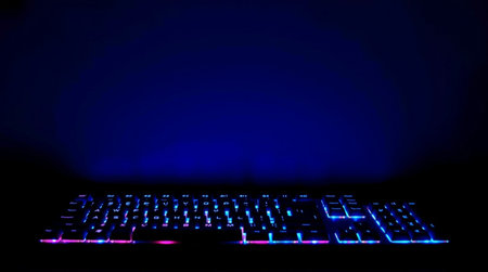 Computer keyboard with blue and pink neon lights on a dark background.の写真素材