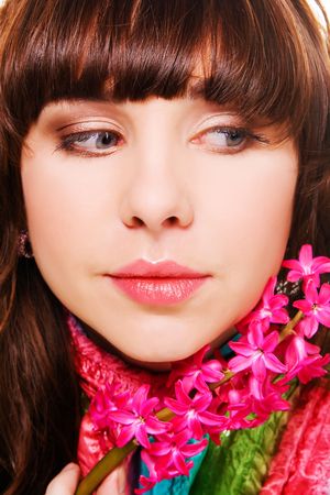 Close-up portrait of a pretty brunette with a pink flowerの写真素材