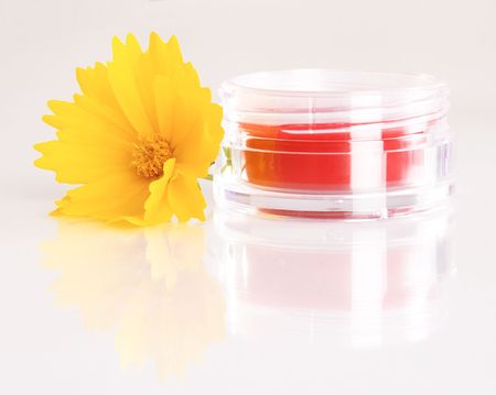 Jar of rouge with a yellow flower on white background の写真素材