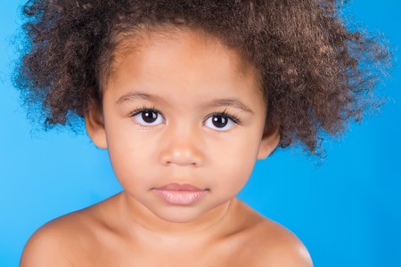 Face portrait of a cute little child on a blue background の写真素材