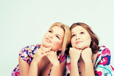 Two lovely pensive girls in colorful dresses