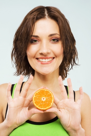 Beautiful happy woman with a half of fresh orange の写真素材