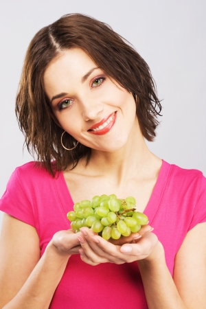 Lovely woman holding a bunch of grapes の写真素材