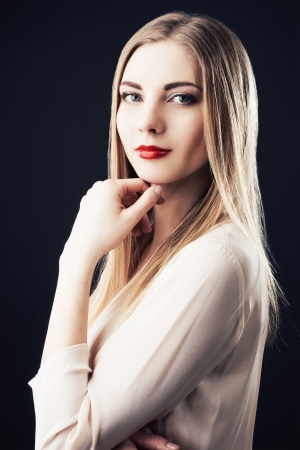 Beautiful woman in chiffon beige blouse against black background の写真素材