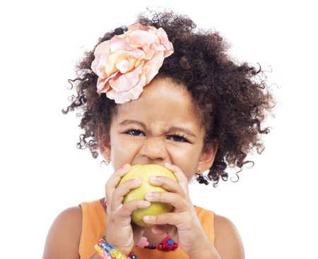 Angry little girl biting an apple, white backgroundの写真素材