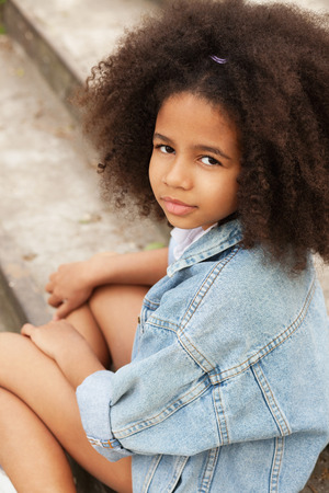 Outdoor portrait of a beautiful little girl wearing jean jacketの写真素材