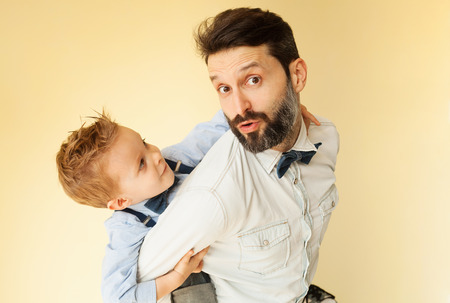Happy little boy enjoying with riding on father's backの写真素材
