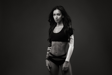 Beautiful lady in sexy sporty clothes against dark backgroundの写真素材