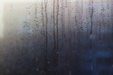 Rainy background with flowing down water drops on window glassの写真素材