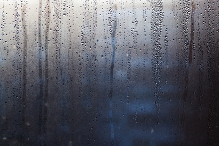 Rainy background with flowing down water drops on window glassの写真素材