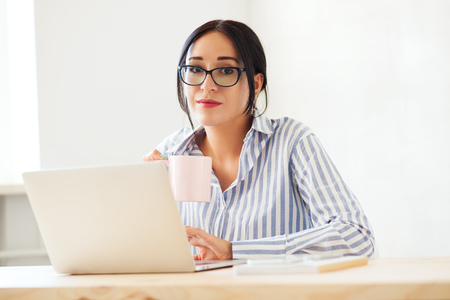 Lovely businesswoman at work with a cup of teaの写真素材