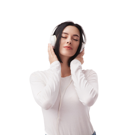 Young beautiful woman enjoying with listening the music in headphones against white backgroundの写真素材