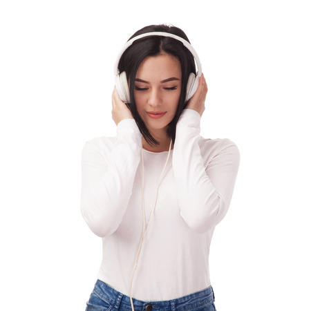 Young beautiful woman enjoying with listening the music in headphones against white backgroundの写真素材