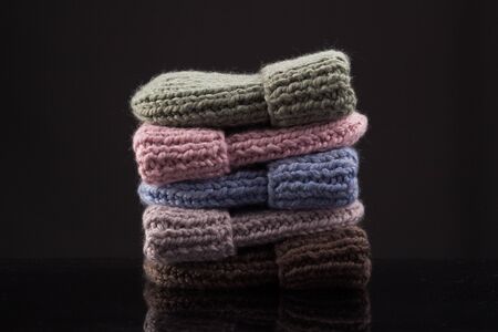 Stack of warm colorful knit hats against dark backgroundの写真素材