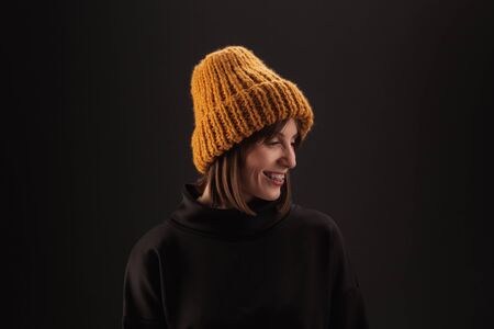 Lovely woman in warm knit hat against dark backgroundの写真素材