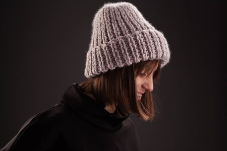 Lovely woman in warm knit hat against dark backgroundの写真素材