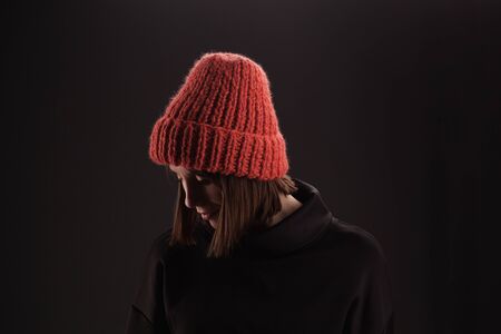 Lovely woman in warm knit hat against dark backgroundの写真素材
