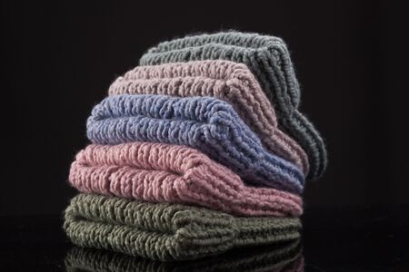 Stack of warm colorful knit hats against dark backgroundの写真素材