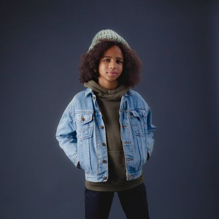 Lovely stylish teenage girl in jean jacket against dark backgroundの写真素材