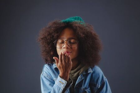 Lovely girl sending an air kiss against dark backgroundの写真素材