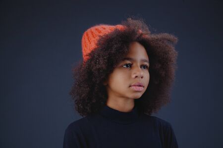 Lovely stylish teenage girl wearing bright knit hat against dark backgroundの写真素材